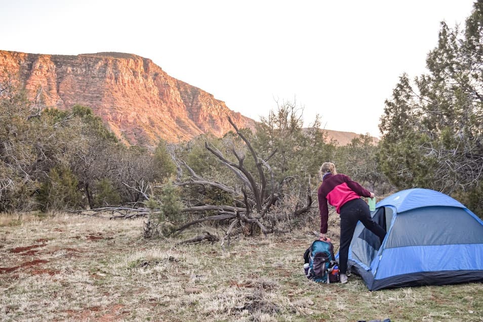 Hiker getting into tent on a backpacking trip in Arizona.