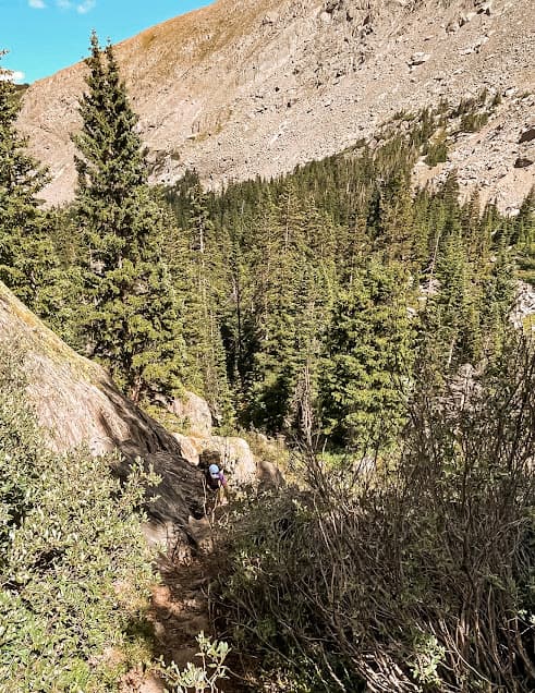 Hiker climbing up rocks and mountains in Colorado.