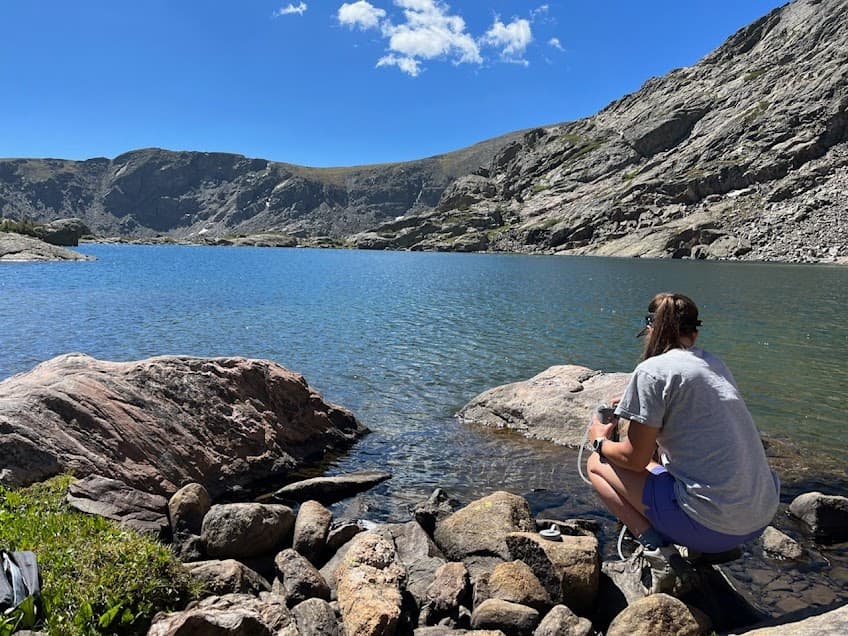 Hiker filters water in Tuhare Lake.
